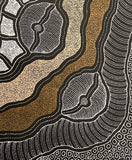 Close-up of a painting by Delvine Pitjara with two organic brown dotted lines surrounded by white dotted shapes on a black background.