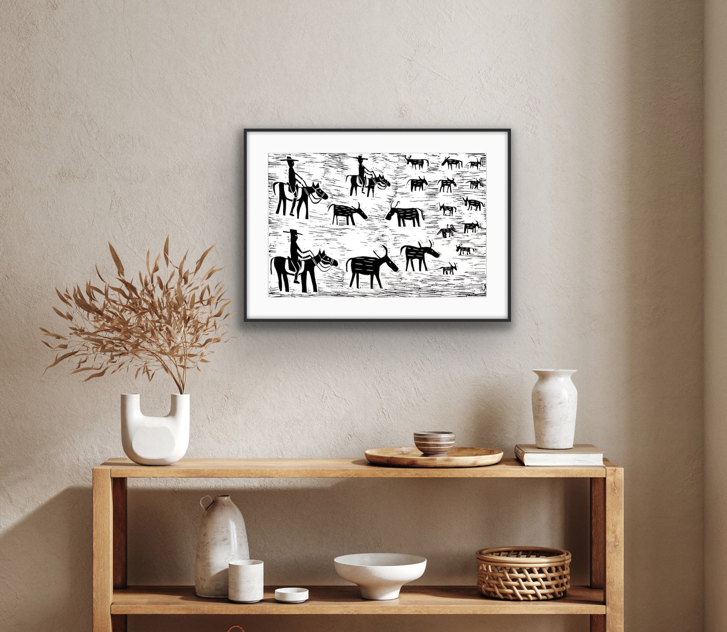 Framed black and white linocut print by Jill Daniels on a wall above a wooden console table with decorative items.