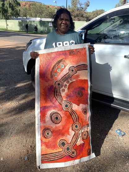 Teresa Baker holding her painting  representing the creation story of Minyma Malilu Tjukurrpa.