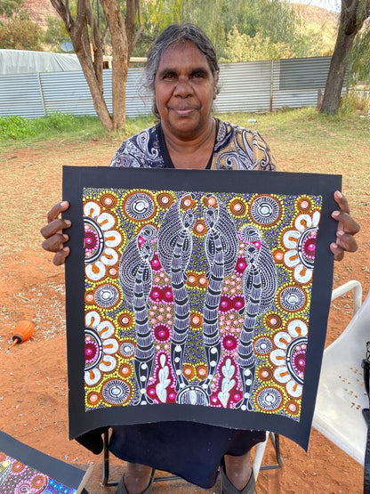 Colleen Wallace Nungarrayi holding her 45x45cm painting depicting her dreamtime sisters story.
