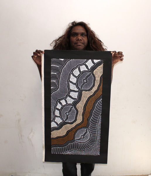 Delvine Pitjara holding her 'My Country' painting 80x40cm White Browns