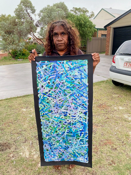 Dora Mbitjana holding her 'Awelye (Body Paint), 2022' painting 104x42cm