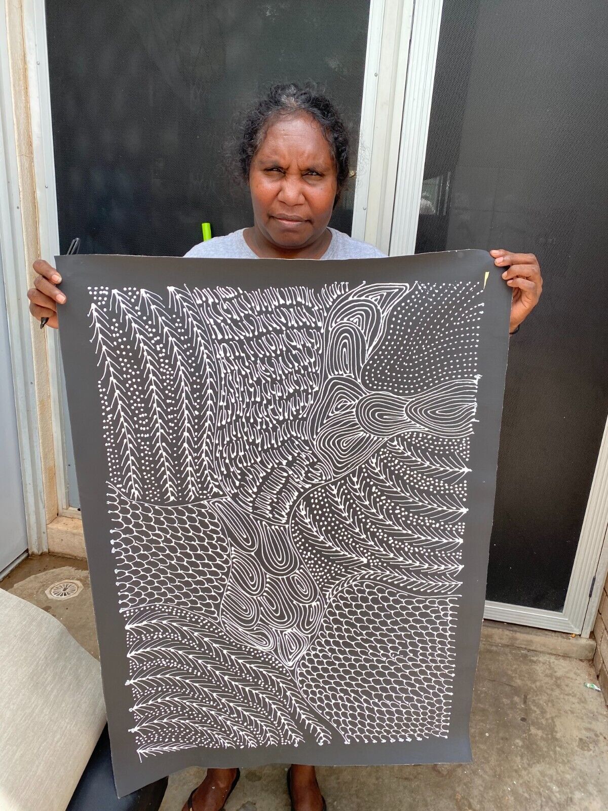 Freda Price Pitjara holding her 'My Country' painting 90x60cm