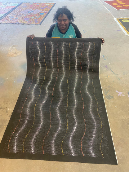 Debbie Brown Napaljarri holding her 'Bush Tomato Dreaming (Wanakiji Jukurrpa)' painting 95x150cm Unstretched White Orange Yellow