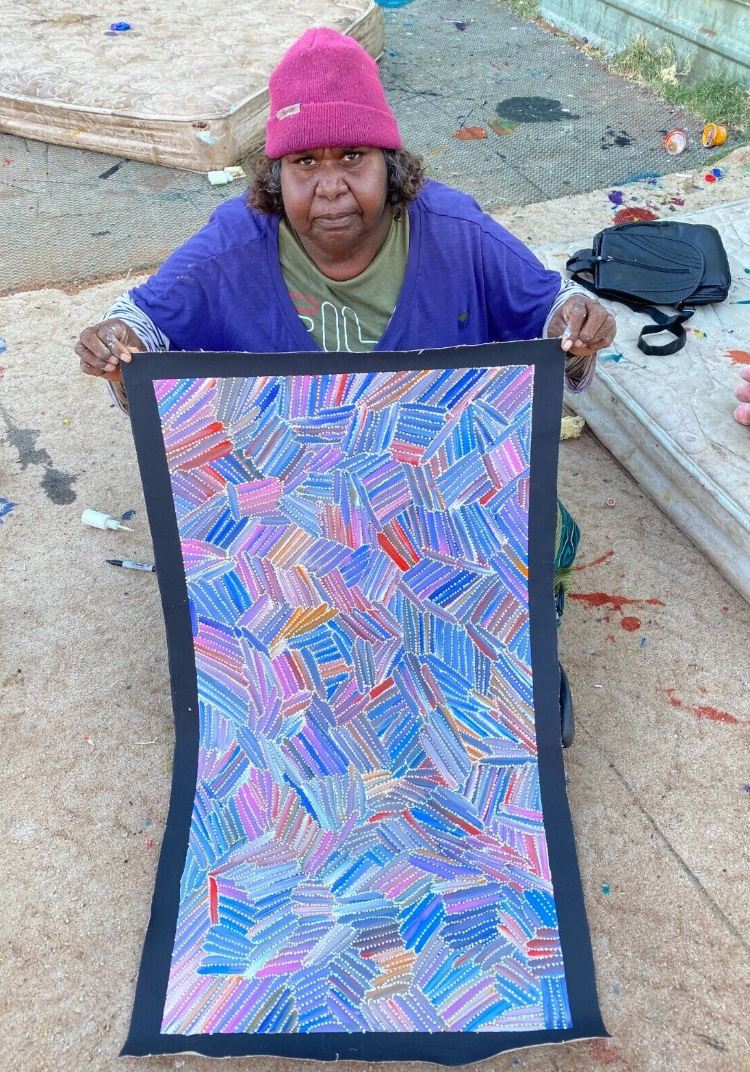 Jedda Purvis Kngwarreye holding her pencil yam dreaming painting.