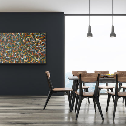 A painting by Selina Numina Kamprina hanging on a black wall beside a dining table and wooden chairs.