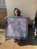 Eileen Bird Kngwarreye holding her 'Arlatyeye (Pencil Yam) Dreaming' painting 60x60cm Multi