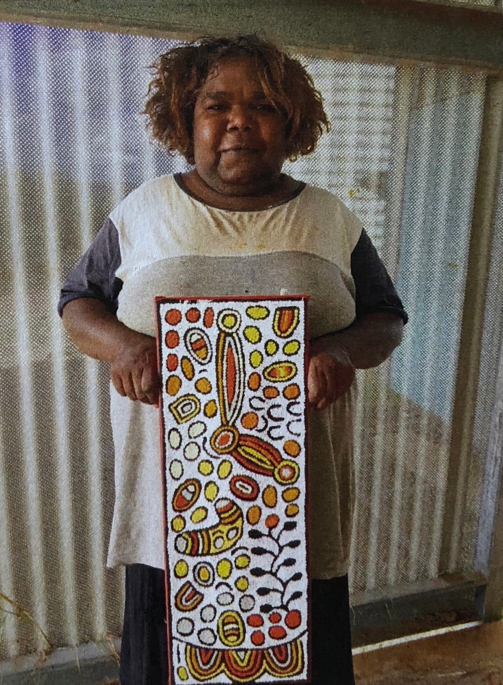 Daphne Larry Nampitjinpa holding her 'My Country' painting 22x60cm