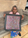 Eileen Bird Kngwarreye holding her 'Arlatyeye (Pencil Yam) Dreaming' painting 45x45cm Multi