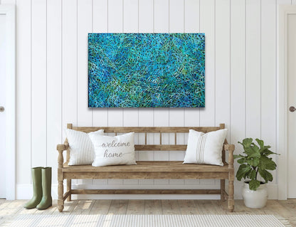 An awelye painting by Betty Club Mbitjana in blue, green, aqua and white colours hanging on a wall above a wooden bench seat.