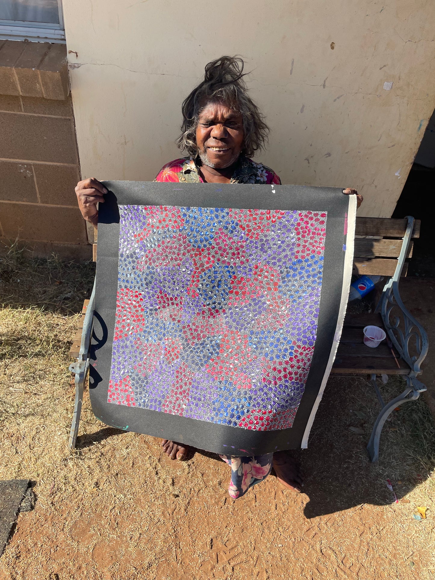 Eileen Bird Kngwarreye holding her 'Arlatyeye (Pencil Yam) Dreaming' painting 60x60cm Multi