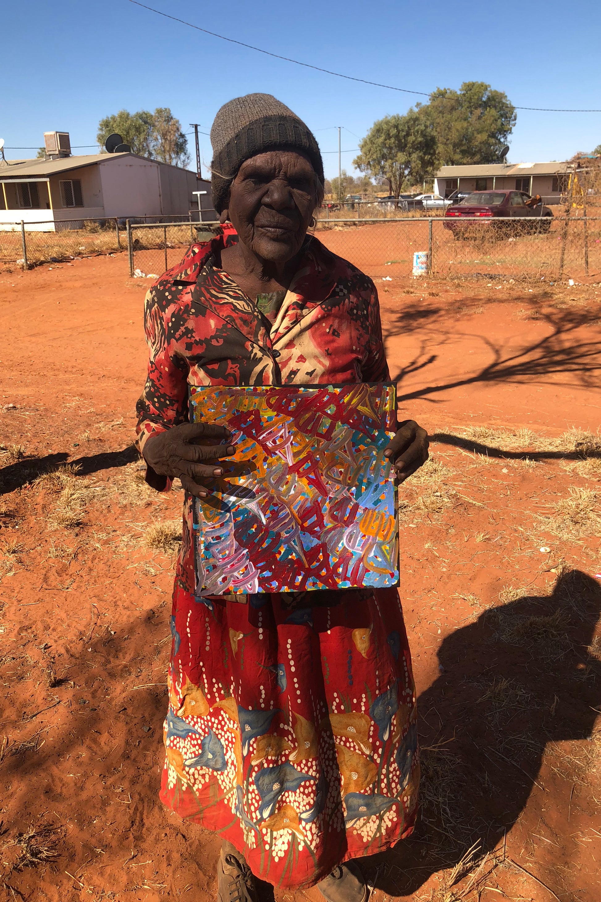 Emily Pwerle holding her 'Awelye (Women's Ceremony)' painting, 30x30cm