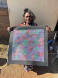 Eileen Bird Kngwarreye holding her 'Arlatyeye (Pencil Yam) Dreaming' painting 60x60cm Multi