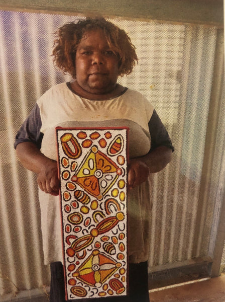 Daphne Larry Nampitjinpa holding her 'My Country' painting 21x60cm