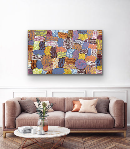 An awelye painting by Betty Club Mbitjana hanging on a white wall above a sofa and marble coffee table.
