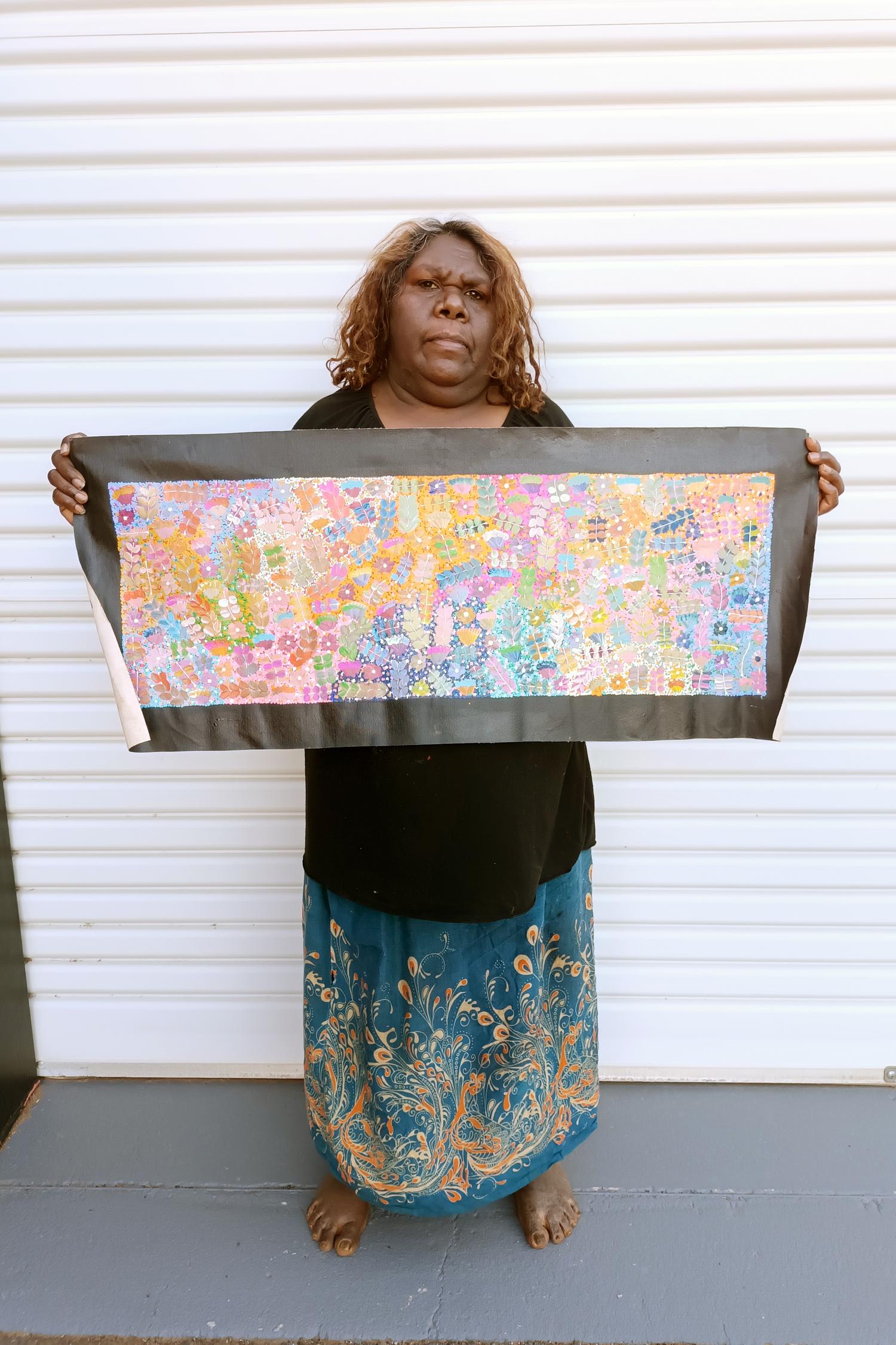 Joycie Morton Petyarre holding her 'Bush Medicine' painting, 30x90cm 