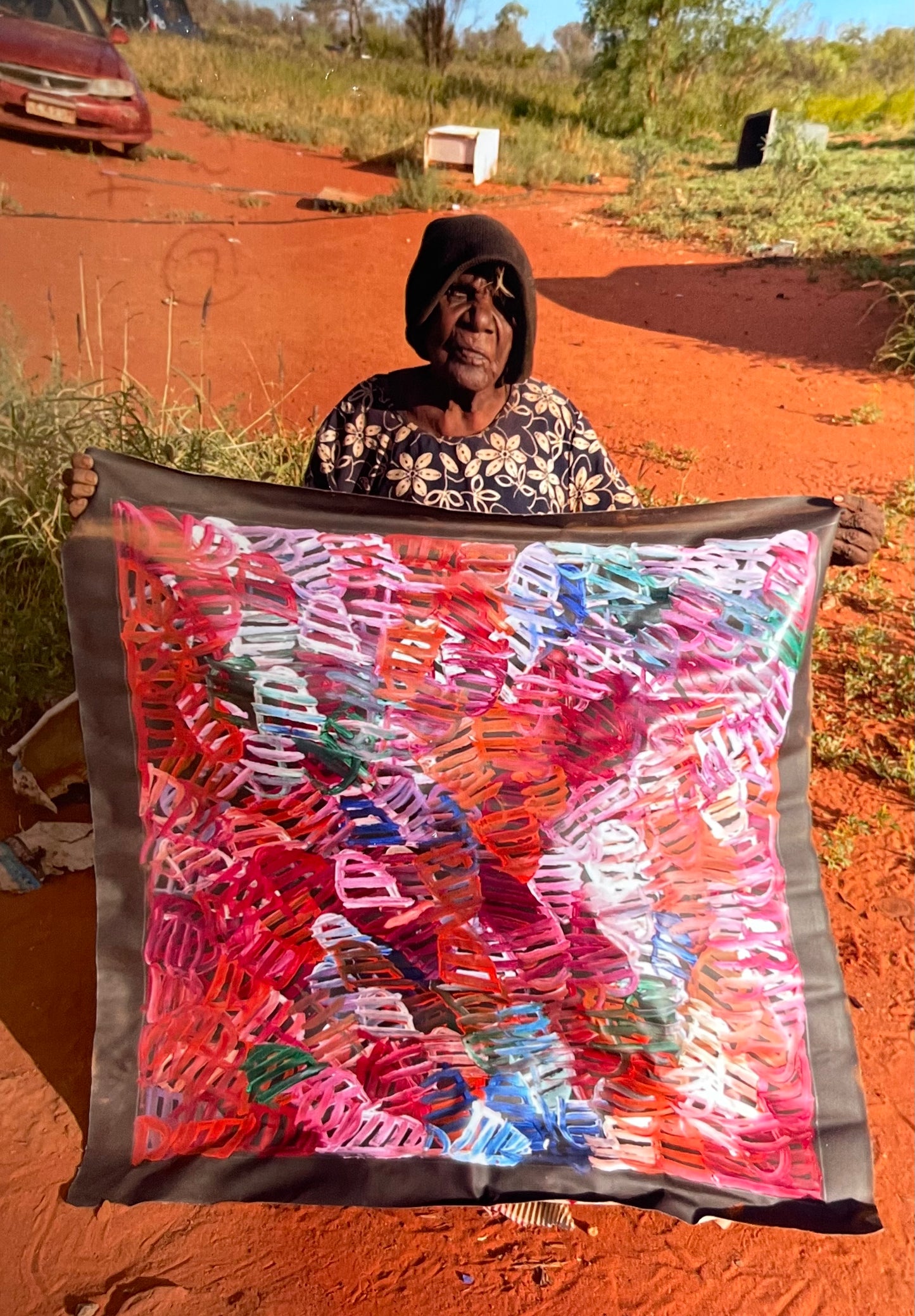 Emily Pwerle holding her 'Awelye (Women's Ceremony) Atnwengerrp' painting 90x90cm