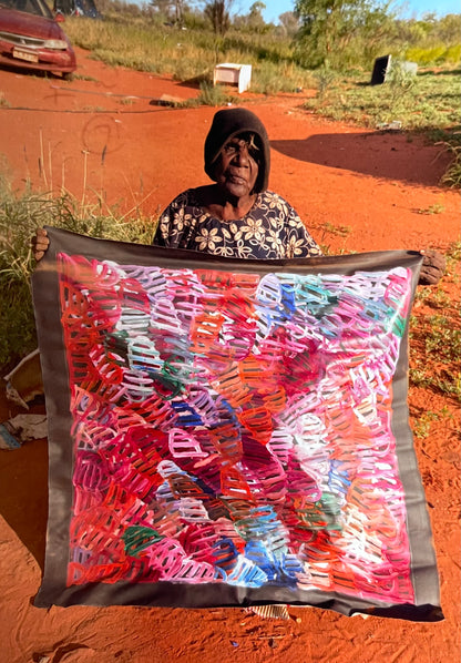 Emily Pwerle holding her 'Awelye (Women's Ceremony) Atnwengerrp' painting 90x90cm