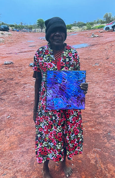 Emily Pwerle holding her 'Awelye (Women's Ceremony) Atnwengerrp' painting 30x30cm
