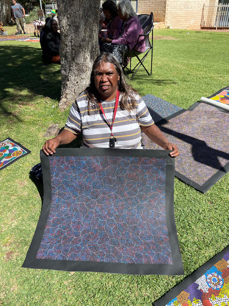 Annie Nelson Napangardi holding her 'Bush Seeds' painting, 71x64cm