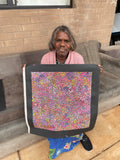 Eileen Bird Kngwarreye holding her 'Arlatyeye (Pencil Yam) Dreaming' painting 45x45cm Multi