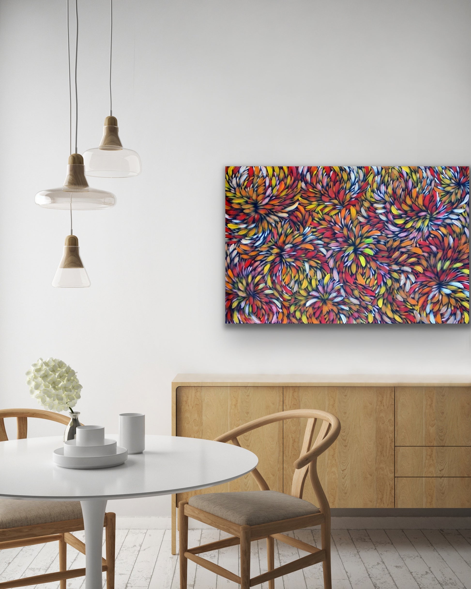 A painting by Selina Numina Kamprina hanging above a woodern console with dining setting.
