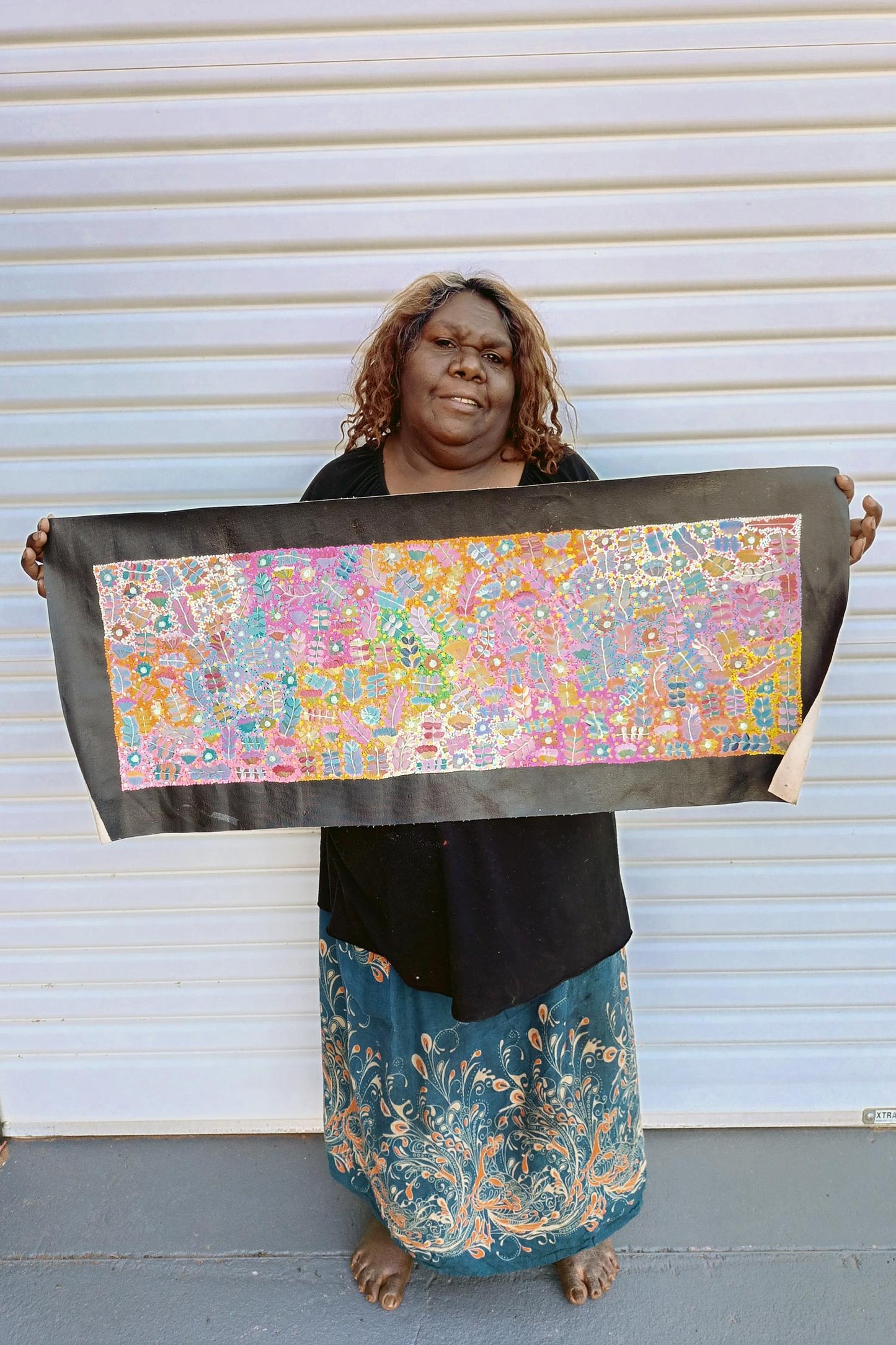 Joycie Morton Petyarre holding her 'Bush Medicine' painting, 30x90cm 