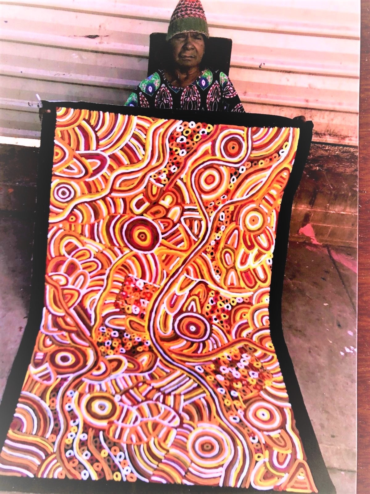 Betty Club Mbitjana holding her My Mother's Dreaming painting 100x150cm Orange Yellow Red