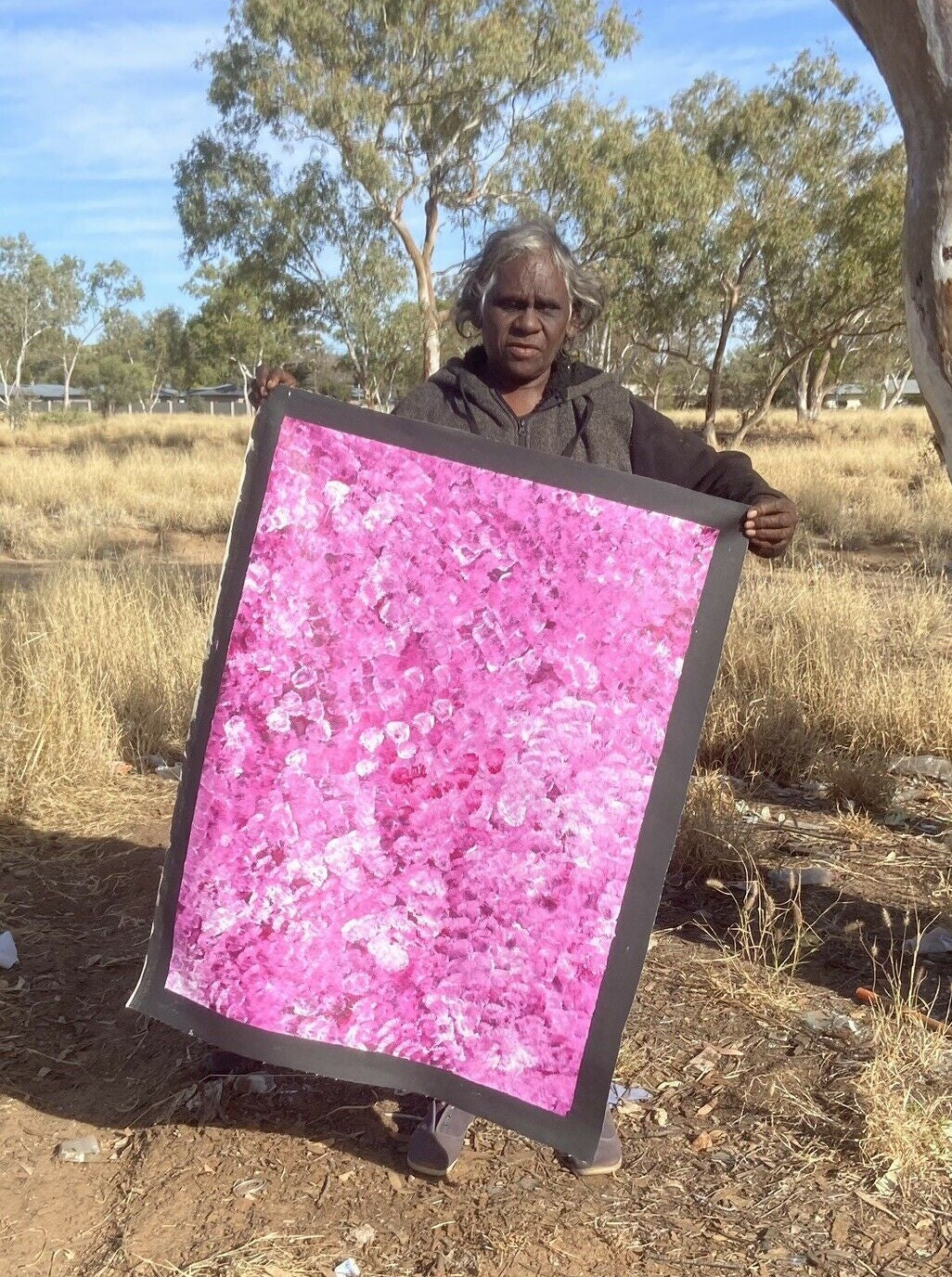 Bessie Pitjara holding her 'Anwekety (Bush Plum)' painting, 90x65cm