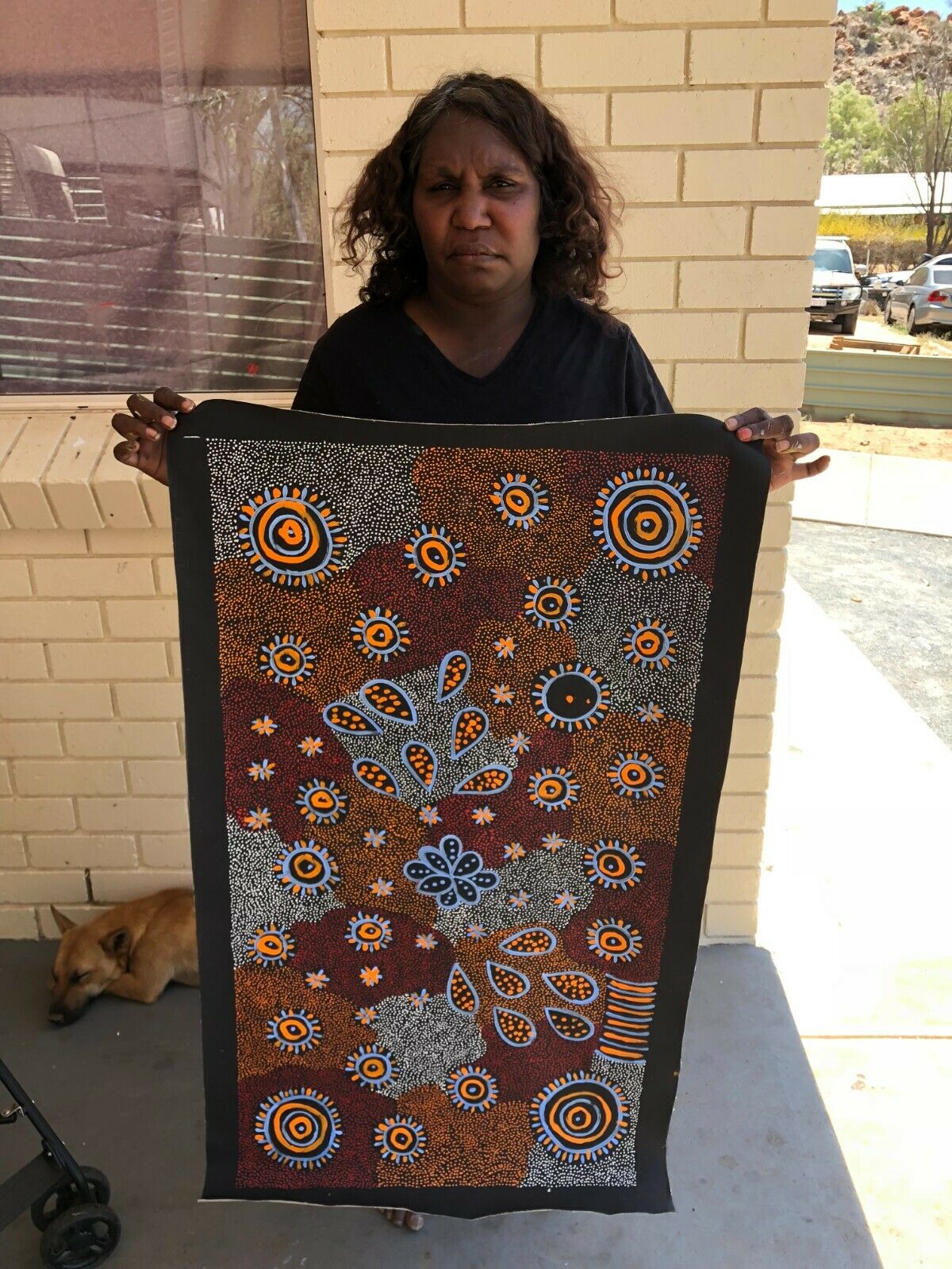 Freda Price Pitjara holding her 'My Country' painting 100x50cm