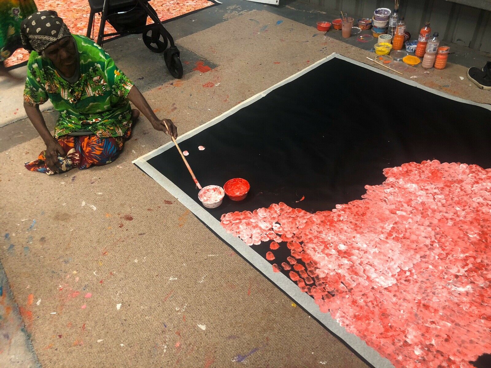 Polly Ngale painting a huge  150x200cm artwork featuring orange tones, representing the 'Bush Plum Dreaming'.