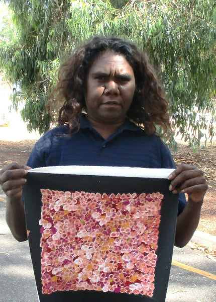 Belinda Golder Kngwarreye holding her Bush Plum Dreaming painting 30x30cm Pink Orange White