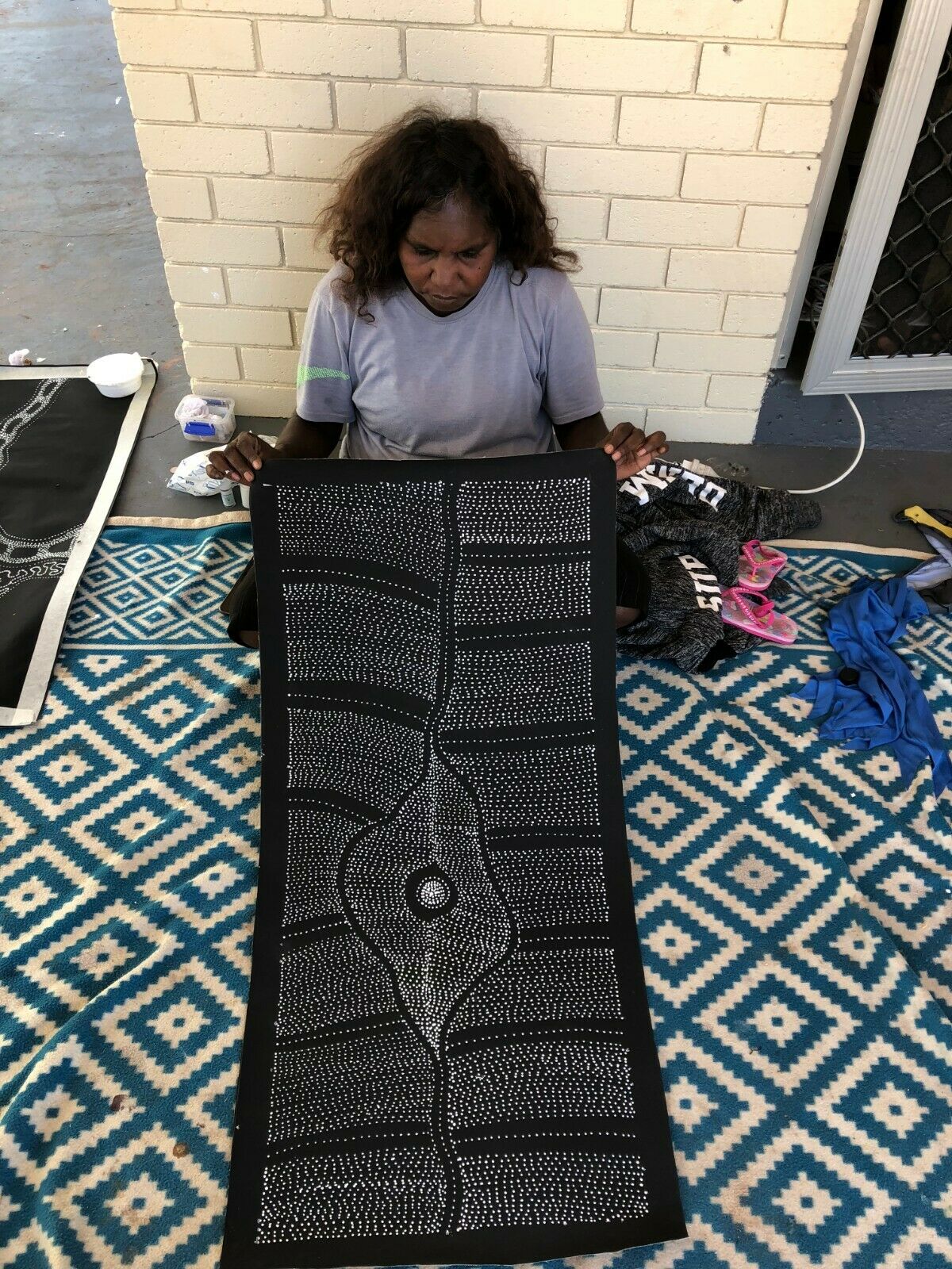 Freda Price Pitjara holding her 'My Country' painting 100x200cm Black and White