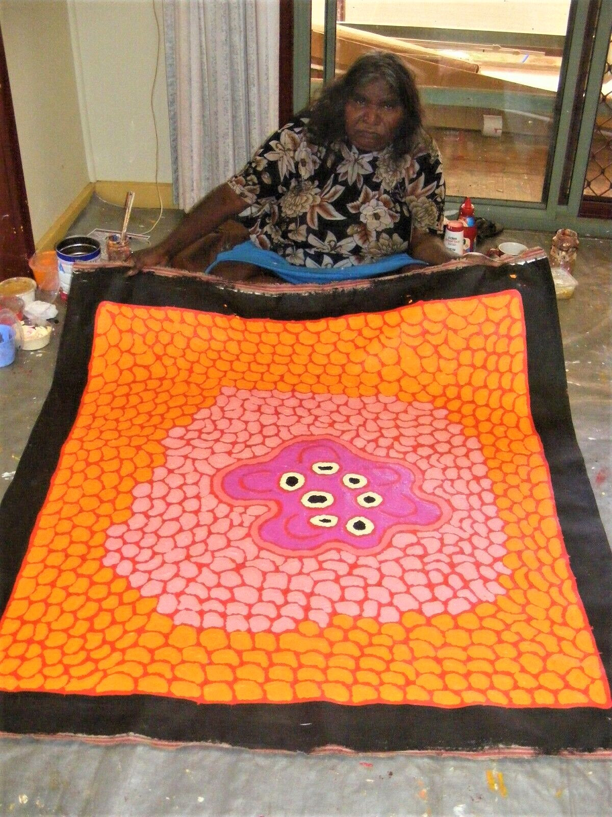Barbara Reid Napangardi holding Women's Waterhole  Orange Red Pink