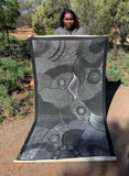 Freda Price Pitjara holding her 'My Country' painting 100x200cm Black and White