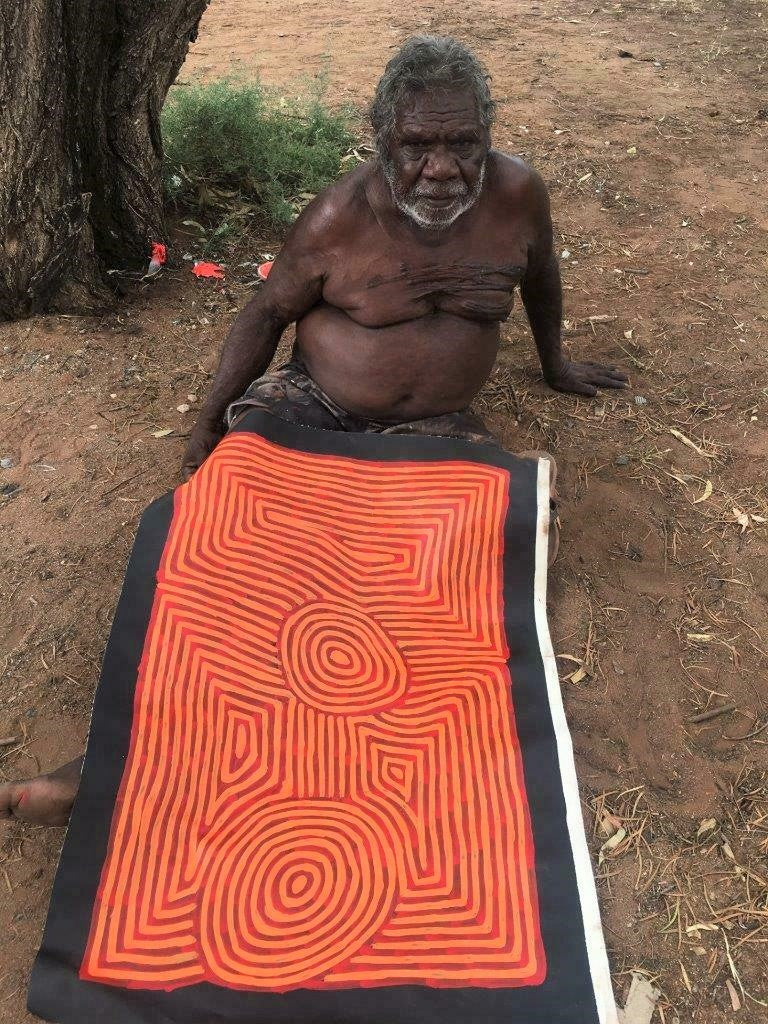 Artist George Hairbrush Tjungurrayi holding his 'Tingari' painting 87x58cm