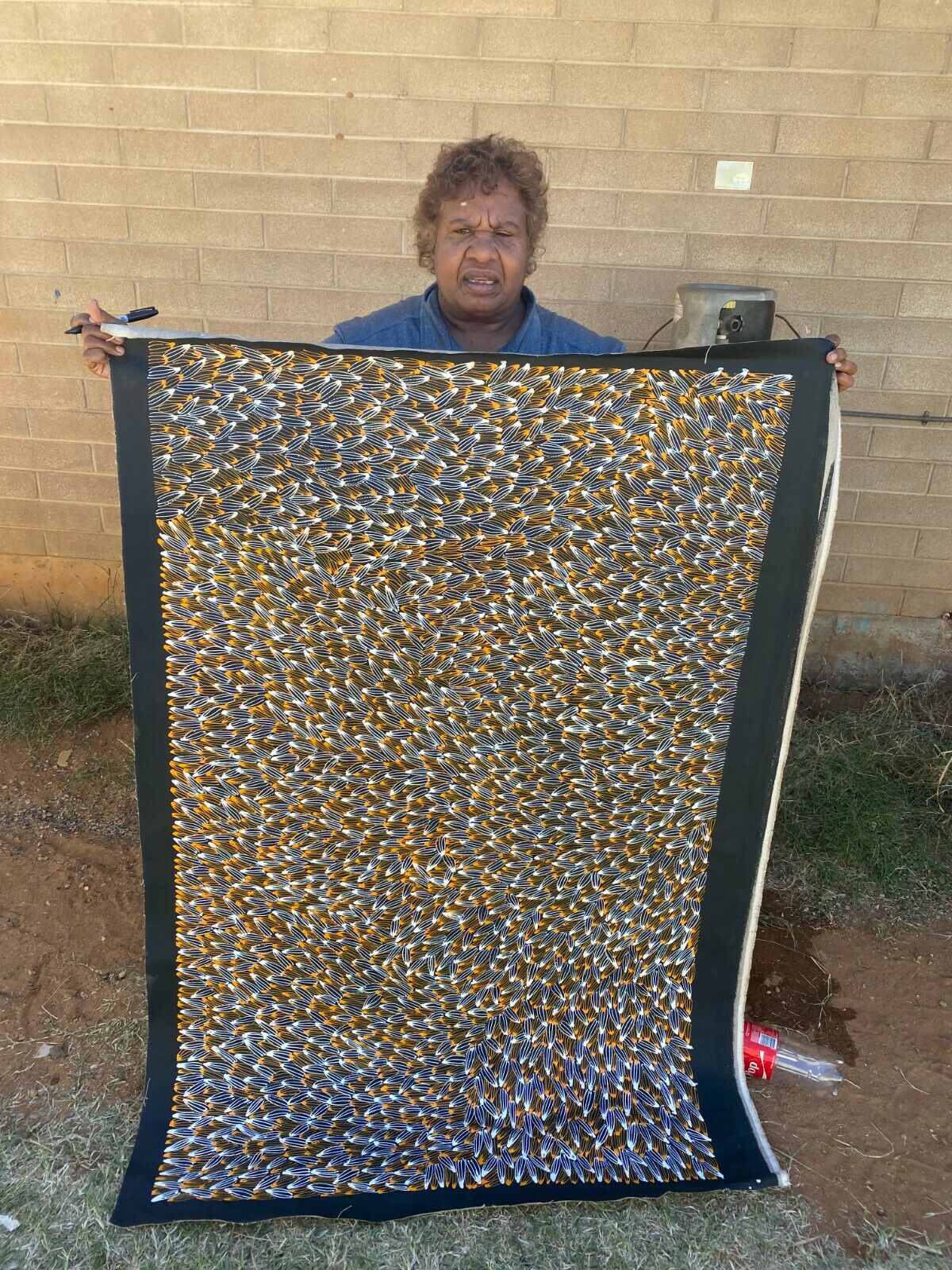 Abie Loy Kemarre holding her 'Bush Medicine Leaf' painting Orange, Black and White 95x150cm
