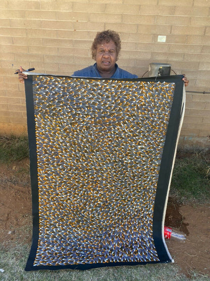 Abie Loy Kemarre holding her 'Bush Medicine Leaf' painting Orange, Black and White 95x150cm