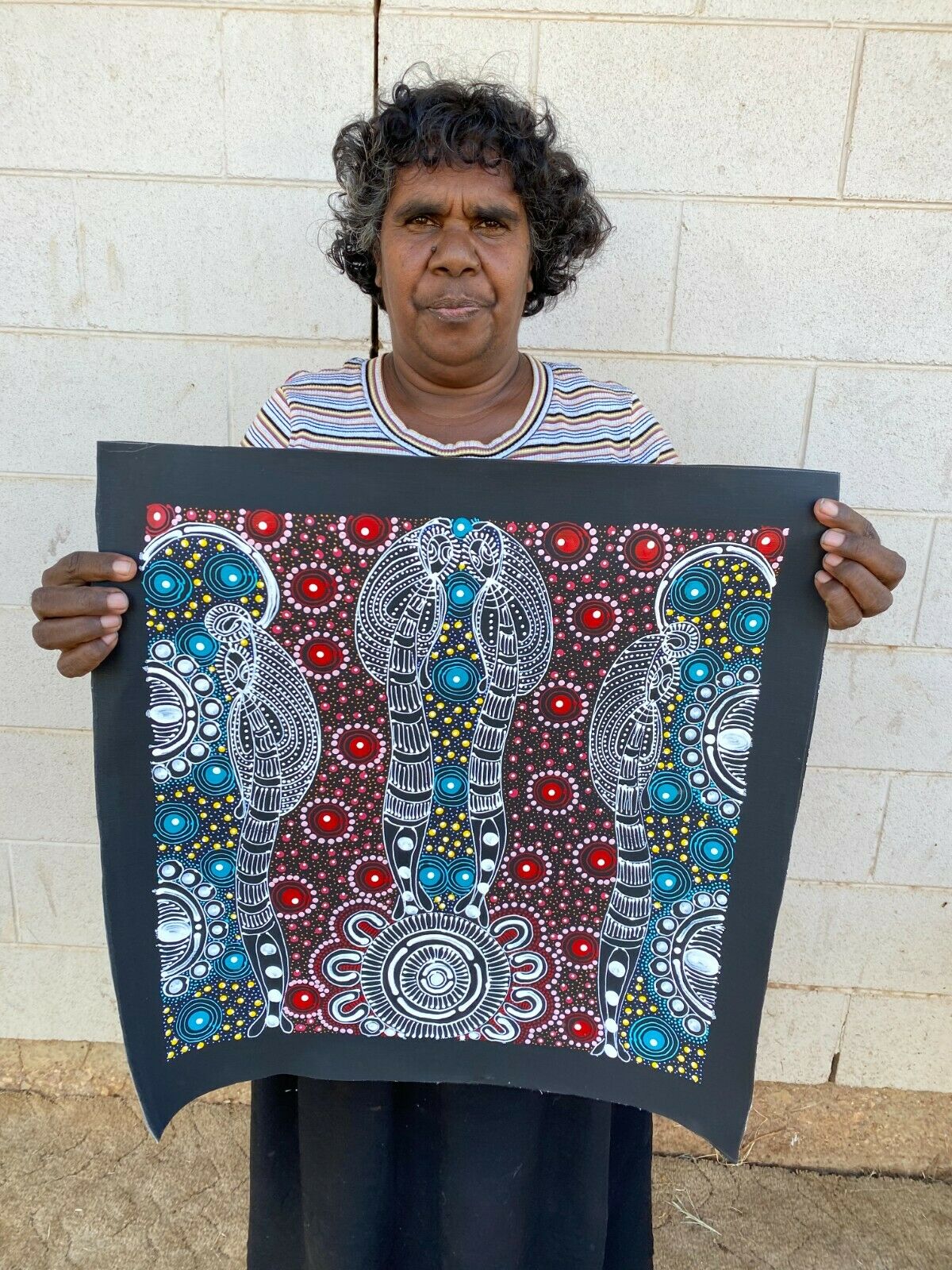 Colleen Wallace Nungarrayi holding her 'Dreamtime Sisters' painting 45x45cm