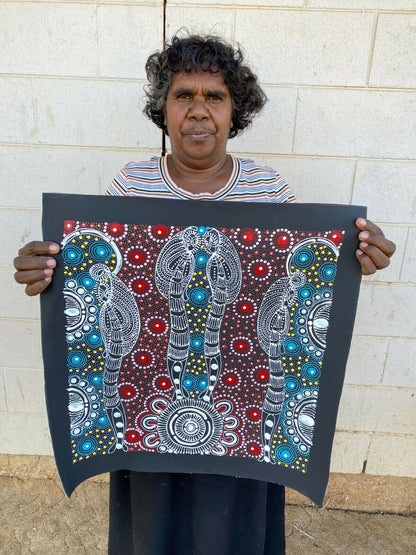 Colleen Wallace Nungarrayi holding her 'Dreamtime Sisters' painting 45x45cm