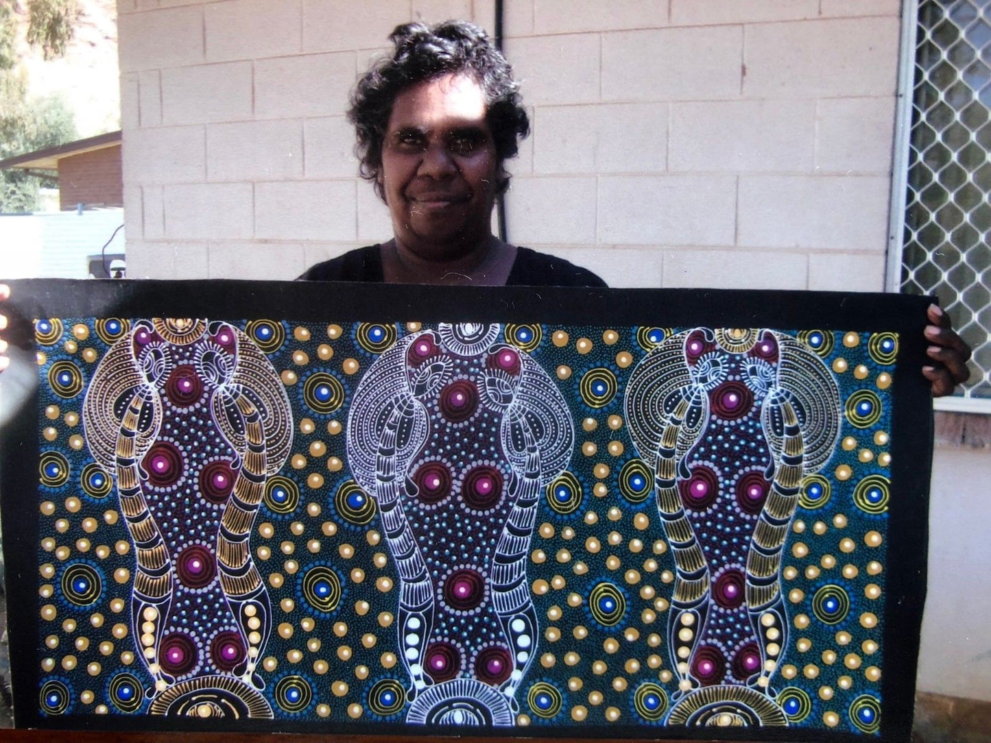 Colleen Wallace Nungarrayi holding her 'Dreamtime Sisters' painting 45x90cm