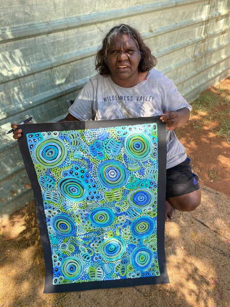 Dulcie Long Pula holding her 'Awelye-Atnwengerrp (Body Paint)' painting 90x60cm Blues Greens