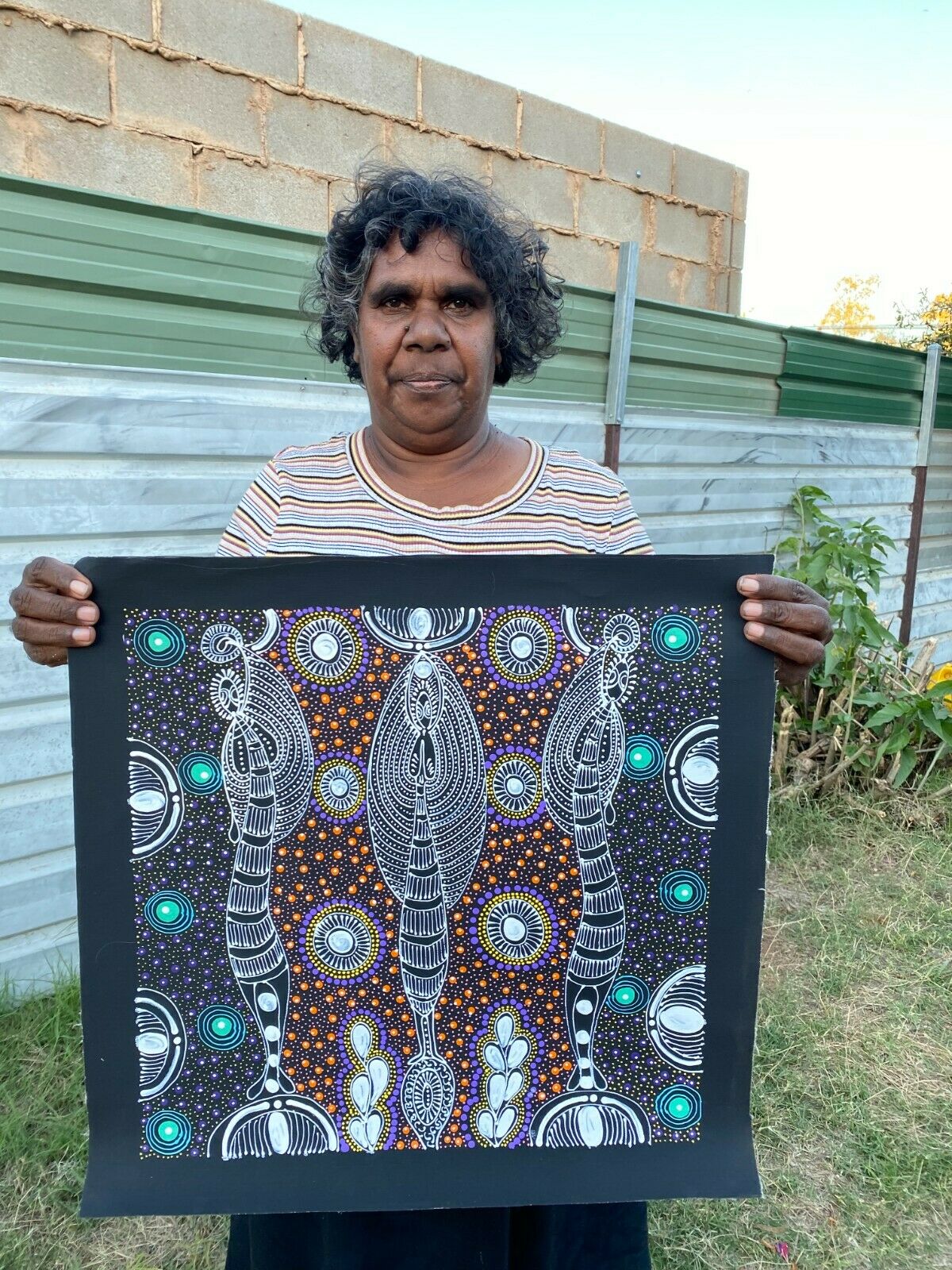 Colleen Wallace Nungarrayi holding her 'Dreamtime Sisters' painting 45x45cm
