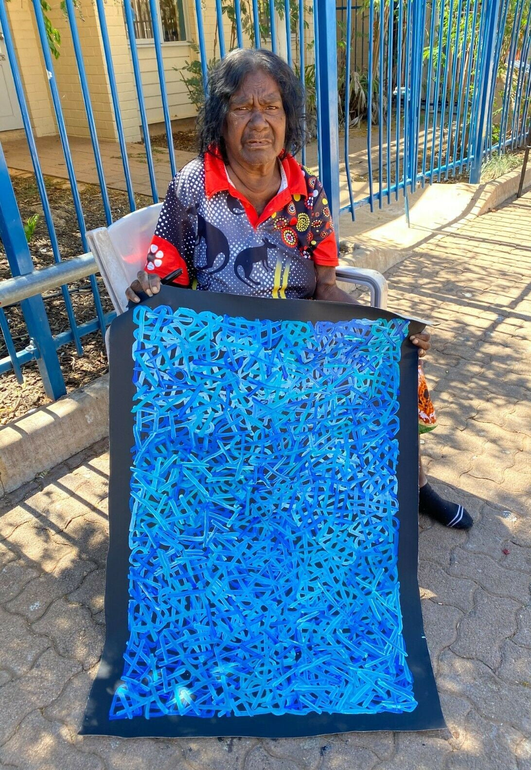 Betty Club Mbitjana 90x60cm holding her painting.