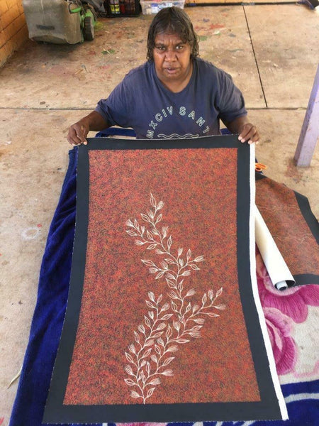 Annie Nelson Napangardi holding her 'Bush Leaves' painting, 95x61cm