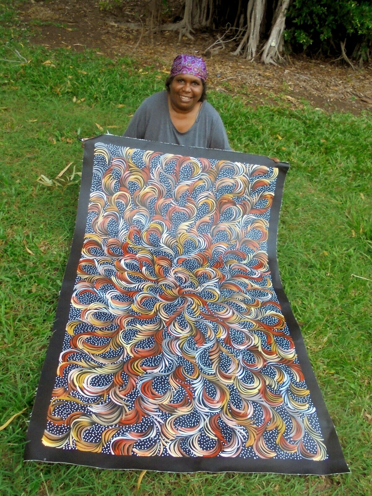 Selina Numina Kamprina holding her bush medicine leaves painting.